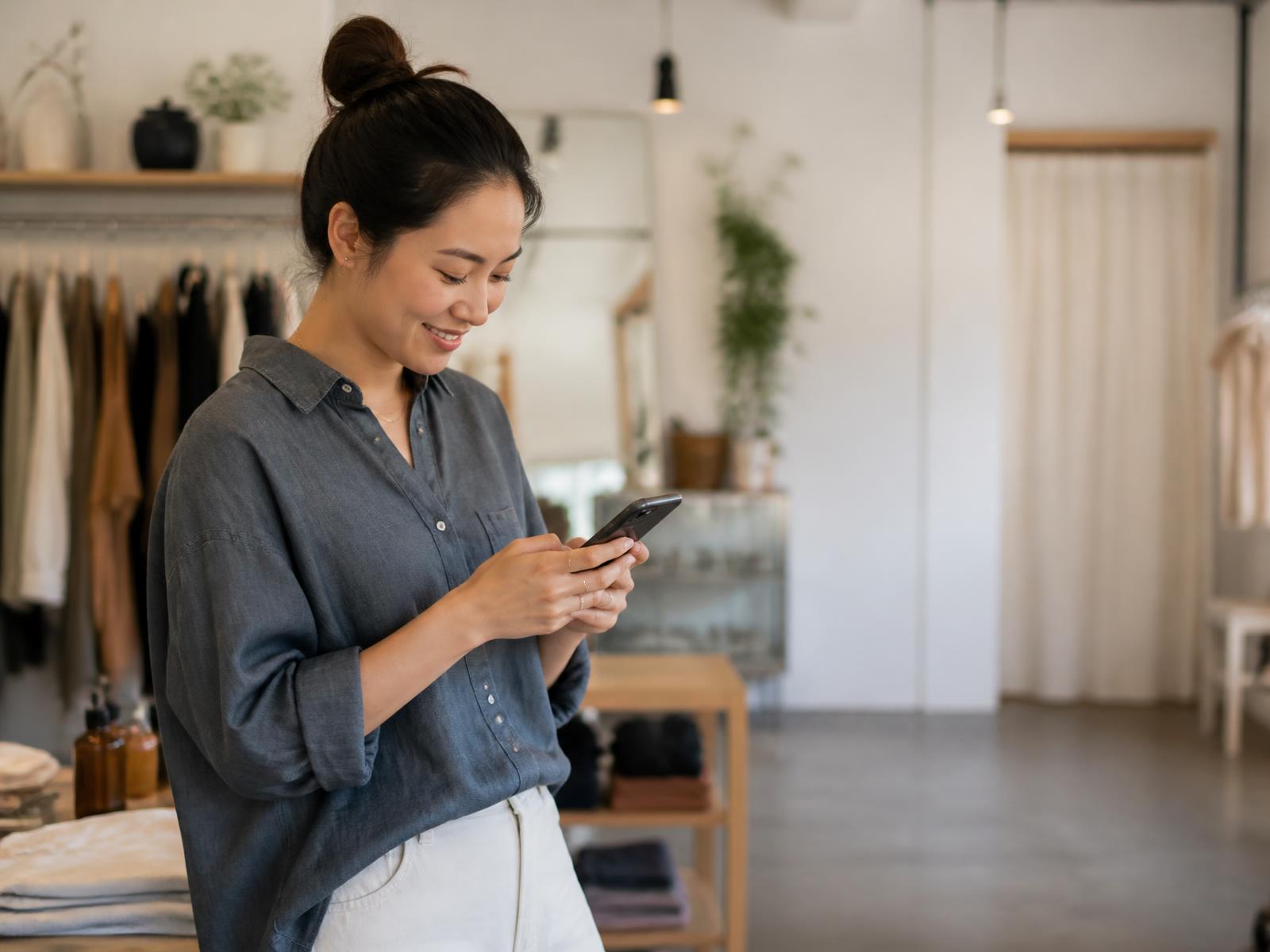 Boutique owner sending a payment request from her phone in her shop